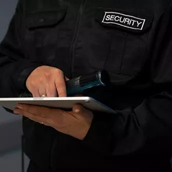 Ein Security Mann, der auf iPad umtippt und Mikrofon in der Hand hält