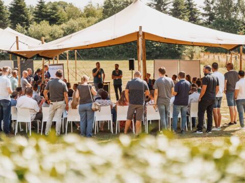 viele menschen auf Wiese unter einem Stretchzelt