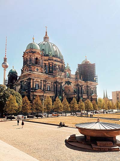 Berliner Dom an einem schönen Sommertag mit blauem Himmel und dem Fernsehturm im Hintergrund.