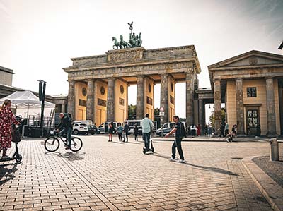 Aufbau für ein Event am Brandenburger Tor, Menschen mit Fahrrad und E-Scooter an einem bewölktem Tag.